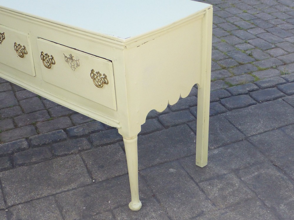 An 18th-century Georgian painted oak dresser base featuring three drawers with decorative brass handles, supported by slender legs with shaped side aprons. View III