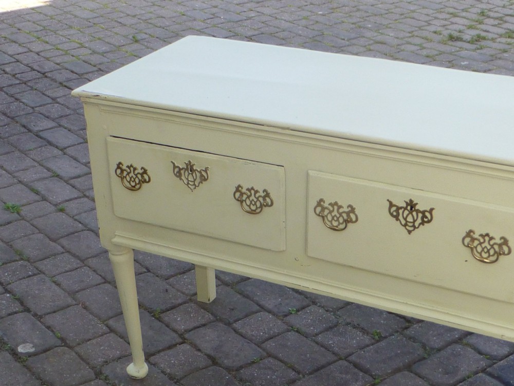 An 18th-century Georgian painted oak dresser base featuring three drawers with decorative brass handles, supported by slender legs with shaped side aprons. View V