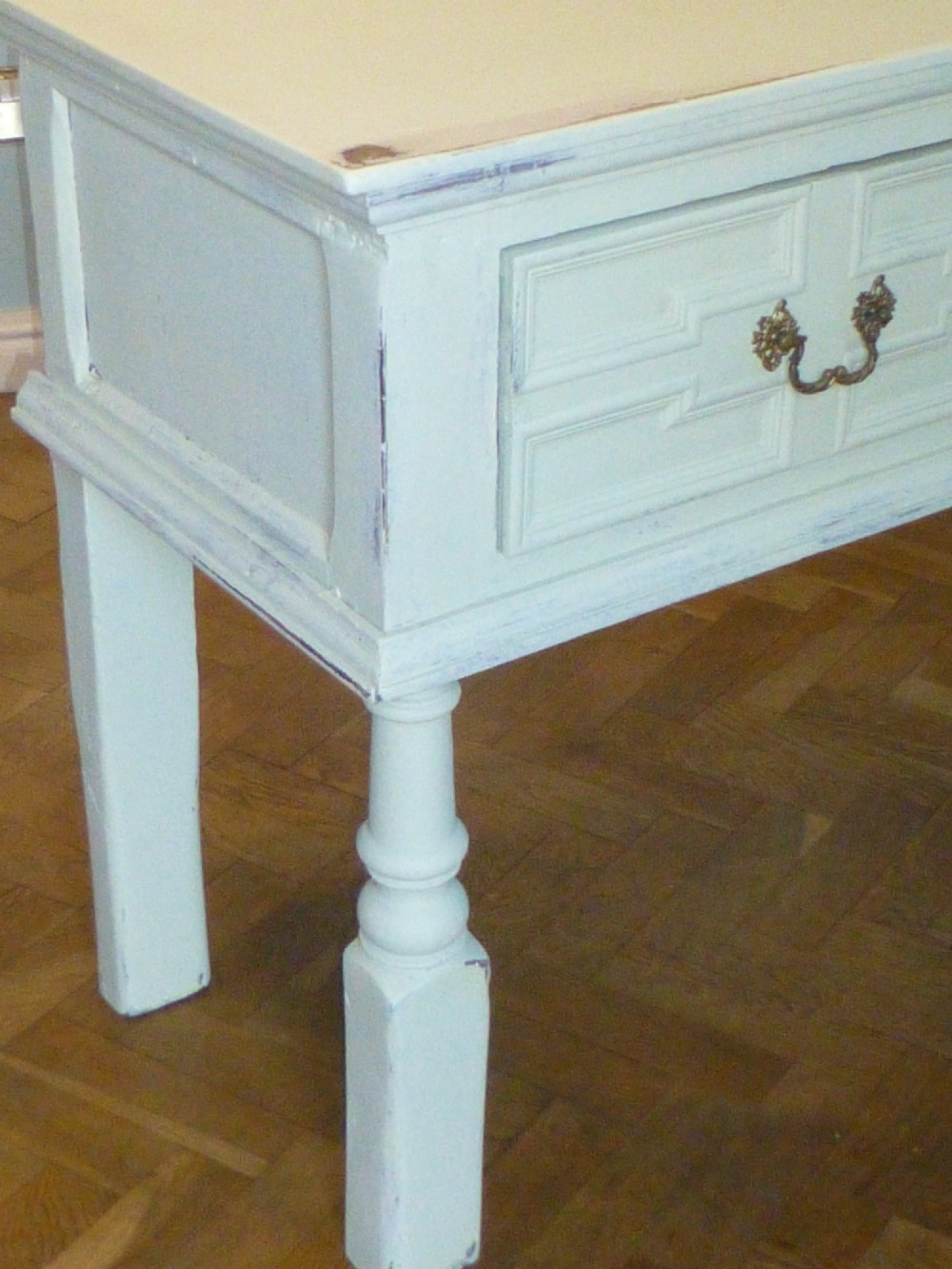 A long, cream-painted 17th-century style oak dresser base featuring three drawers with geometric mouldings, brass drop handles, and turned front legs. View II