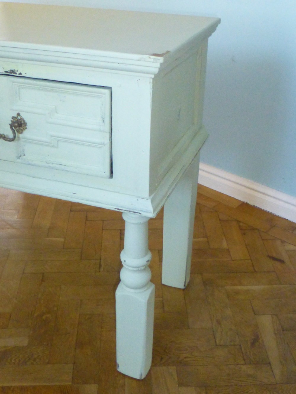 A long, cream-painted 17th-century style oak dresser base featuring three drawers with geometric mouldings, brass drop handles, and turned front legs. View III