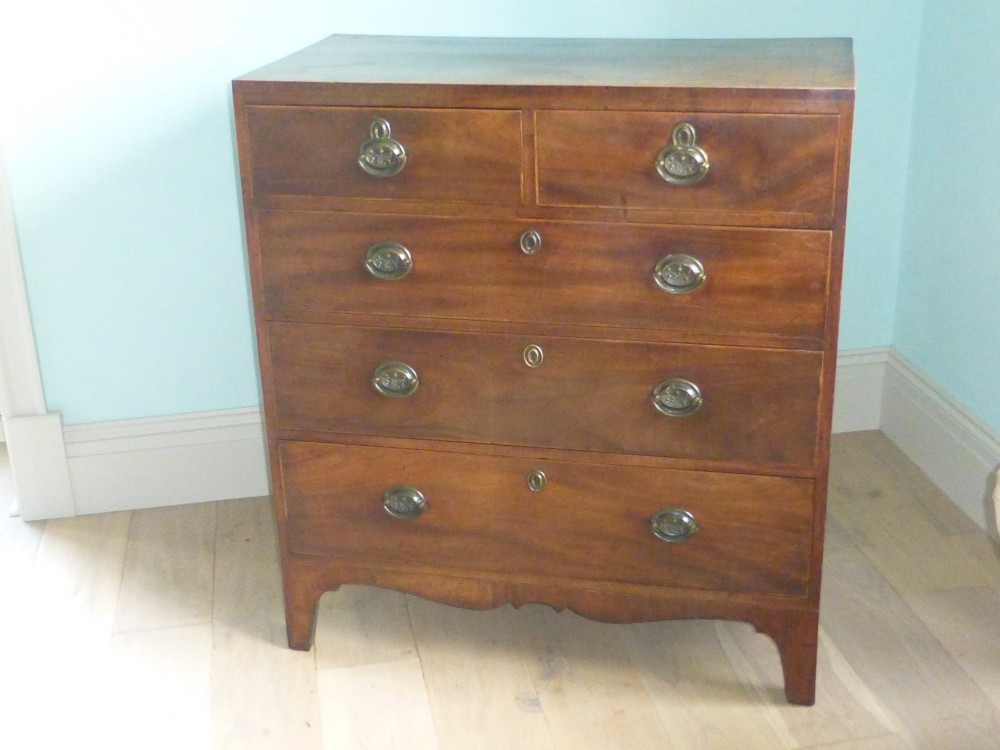 A late eighteenth-century Georgian mahogany chest of drawers with two short drawers over three long graduated drawers, featuring line inlay and oval brass handles.