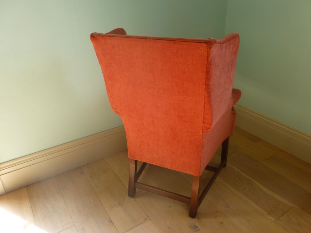 A 19th-century wingback armchair upholstered in terracotta fabric with dark mahogany legs and stretchers. View II