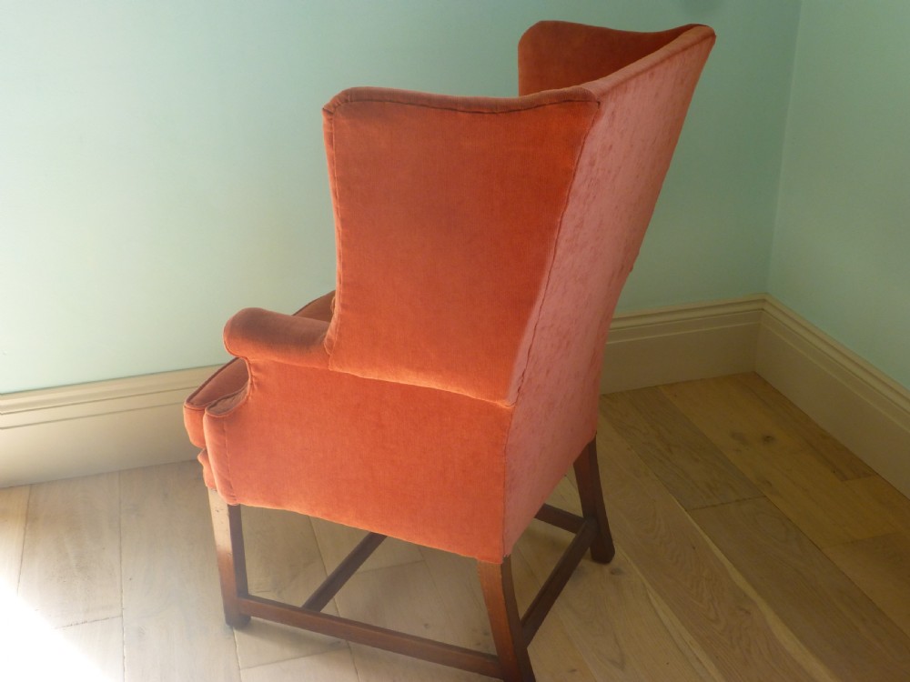 A 19th-century wingback armchair upholstered in terracotta fabric with dark mahogany legs and stretchers. View III