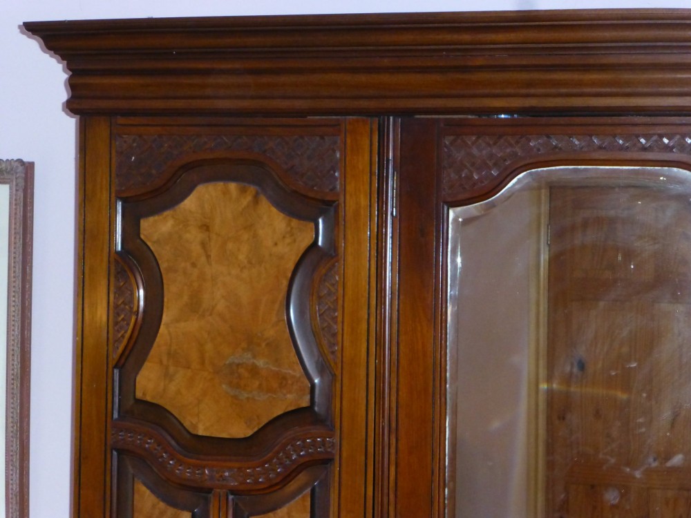A mid-19th-century Victorian triple wardrobe made of rich burr walnut, featuring a central full-length mirror door flanked by two carved panelled doors. View II