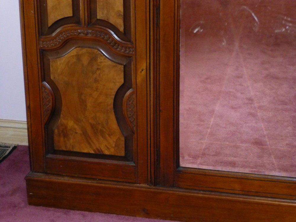 A mid-19th-century Victorian triple wardrobe made of rich burr walnut, featuring a central full-length mirror door flanked by two carved panelled doors. View III