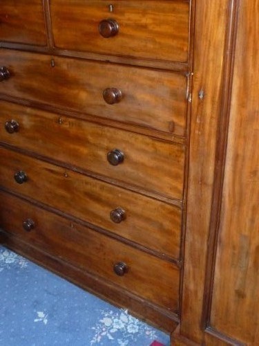 A nineteenth-century mahogany inverted breakfront compactum wardrobe featuring a central chest of drawers beneath small double cupboards, flanked by two tall panelled side wings. View II