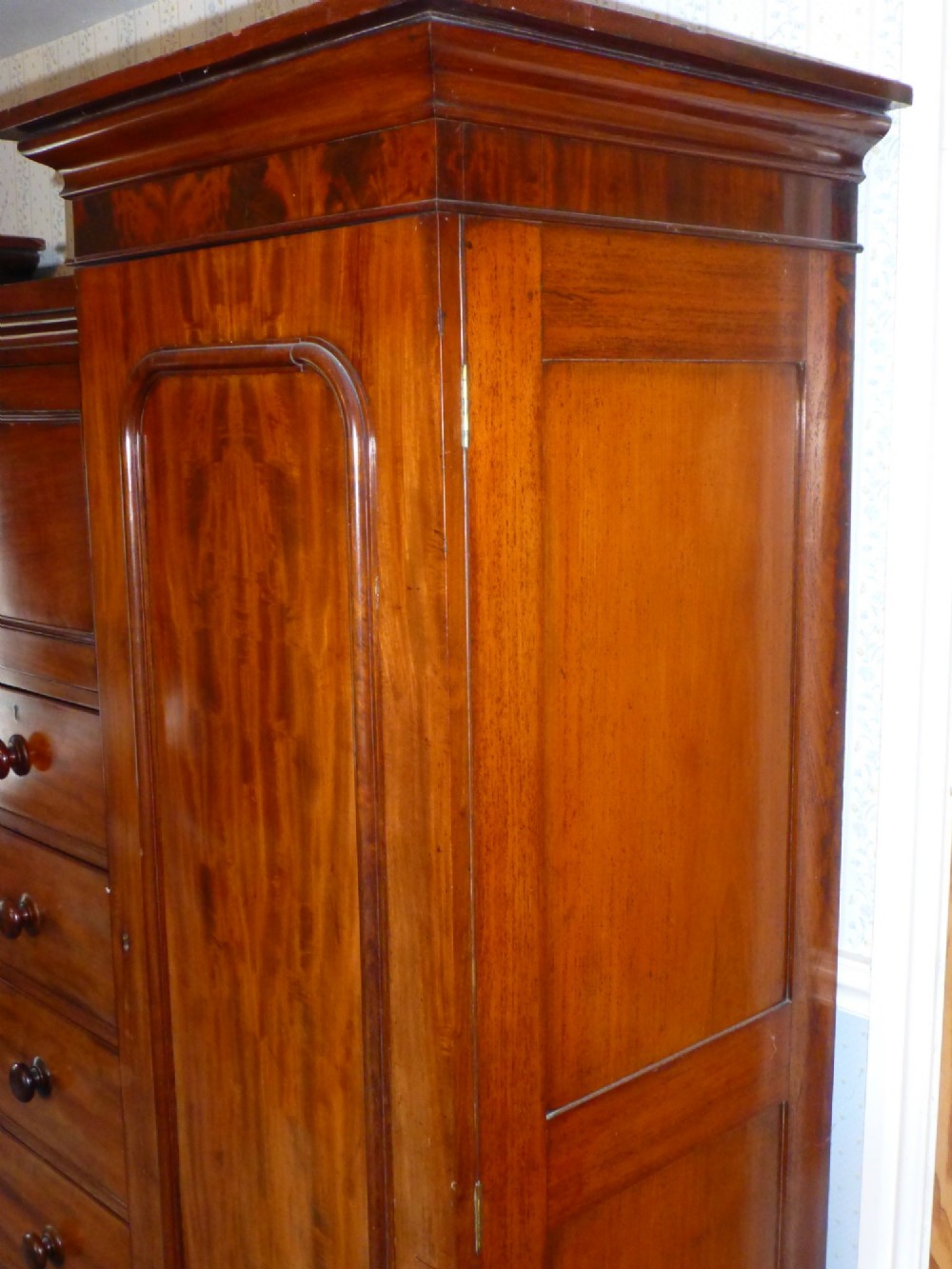A nineteenth-century mahogany inverted breakfront compactum wardrobe featuring a central chest of drawers beneath small double cupboards, flanked by two tall panelled side wings. View V