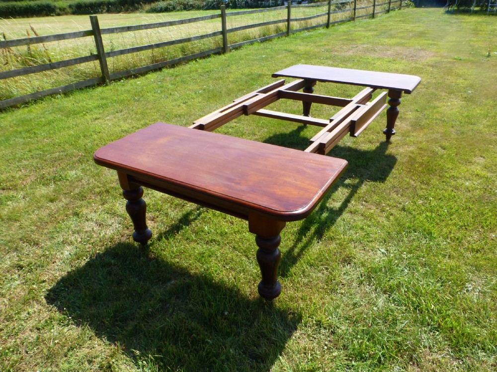 A large Regency extending mahogany dining table featuring a polished rectangular top, three extension leaves, and turned wood legs. View III