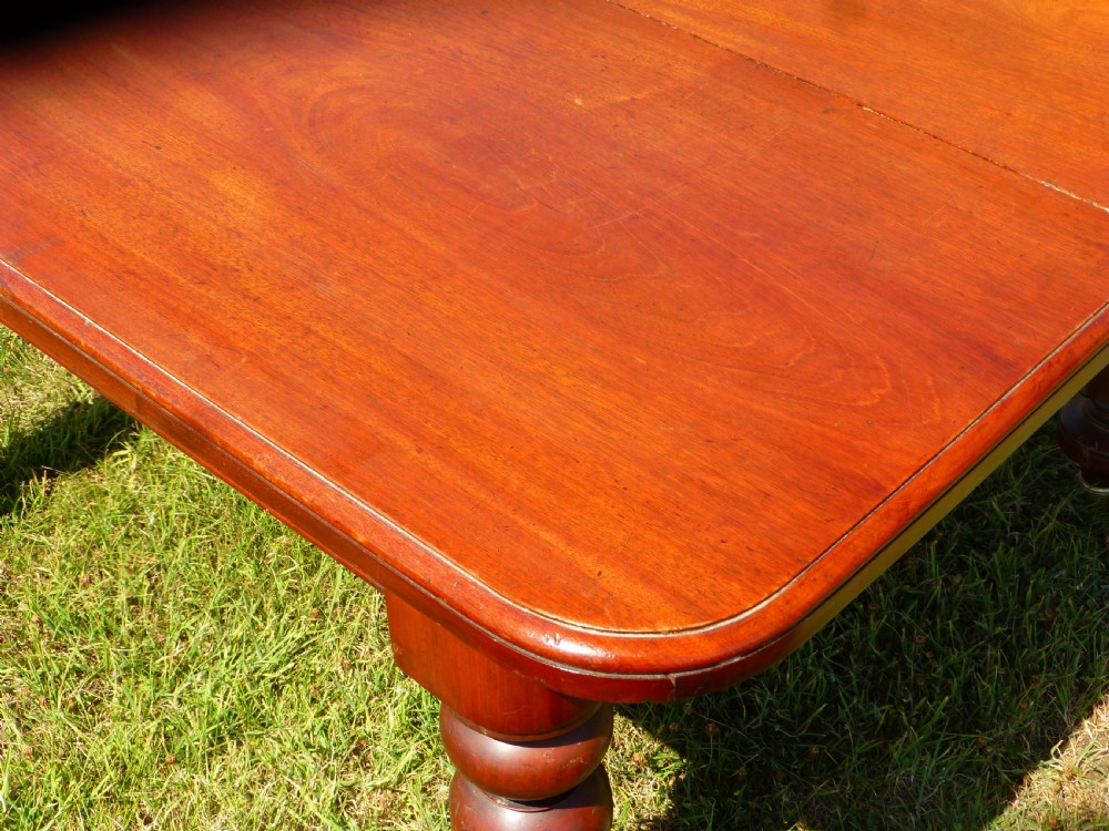 A large Regency extending mahogany dining table featuring a polished rectangular top, three extension leaves, and turned wood legs. View VI
