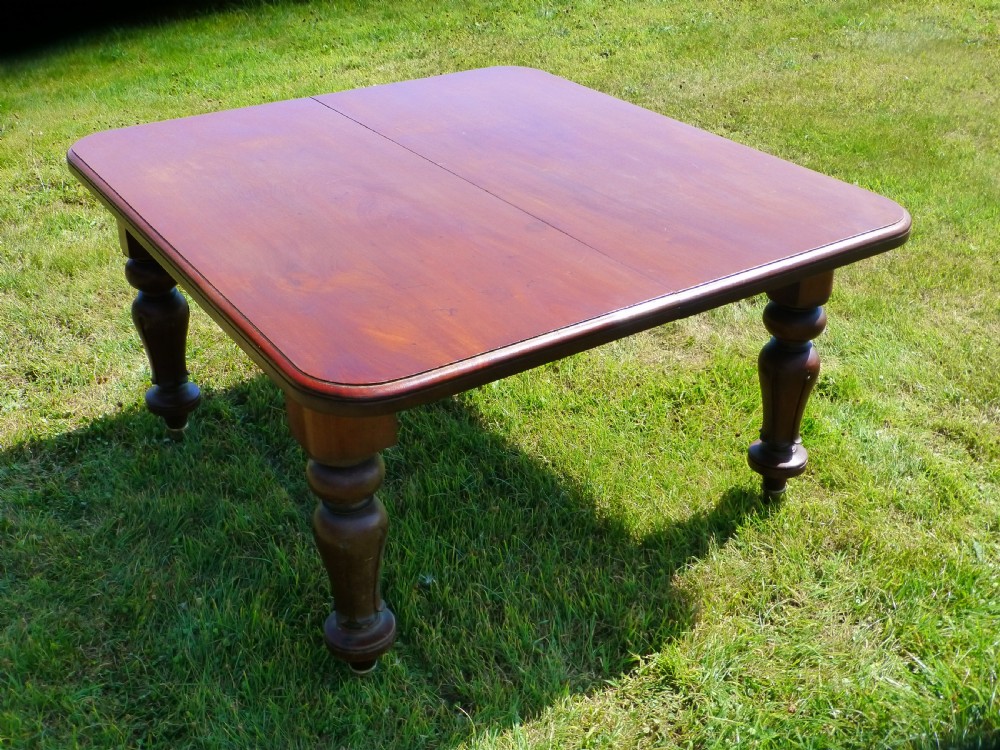 A large Regency extending mahogany dining table featuring a polished rectangular top, three extension leaves, and turned wood legs. View X