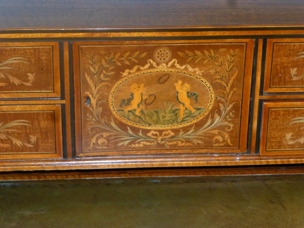 An Edwardian mahogany Carlton House desk featuring intricate floral marquetry inlay, a leather writing surface, and a curved raised tier of drawers. View IV
