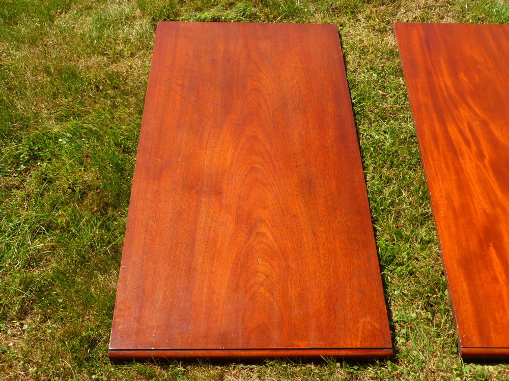 A large mahogany wind-out extending dining table featuring turned legs fitted with brass castors and rounded top corners. View VIII