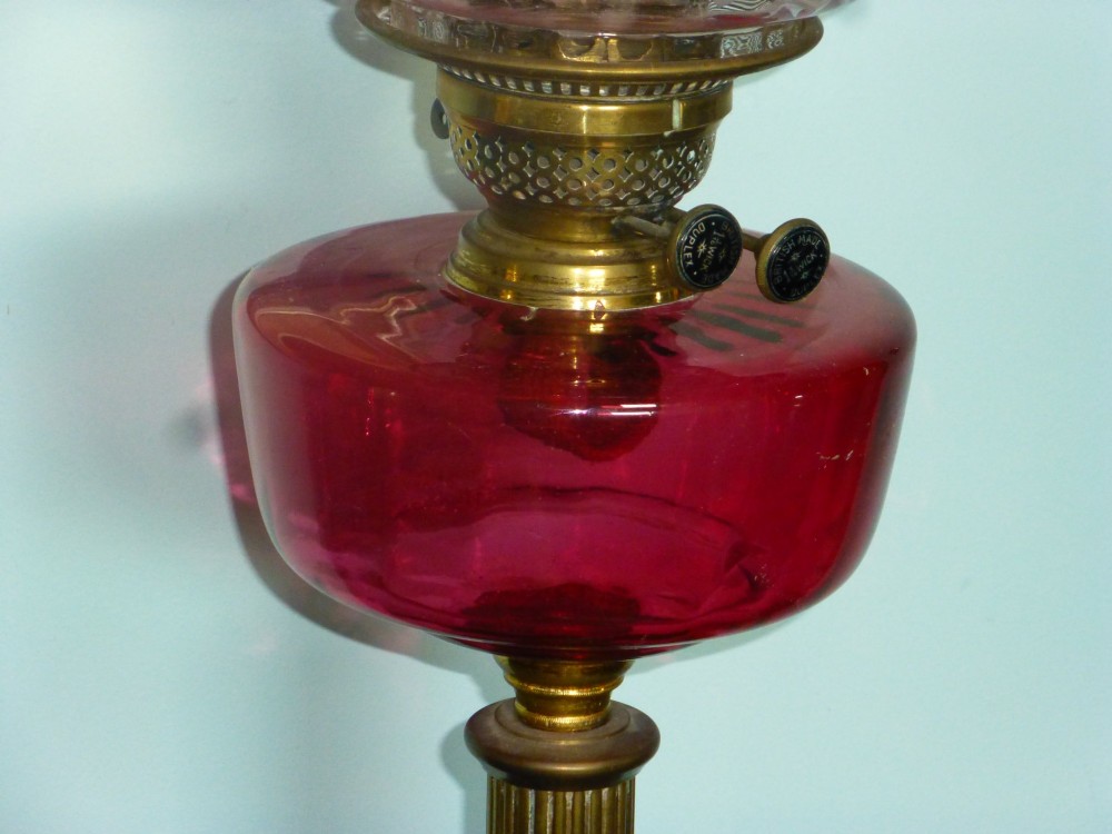 A Victorian cranberry glass and brass duplex oil lamp featuring a fluted column base, red glass reservoir, and a ruffled etched shade. View II