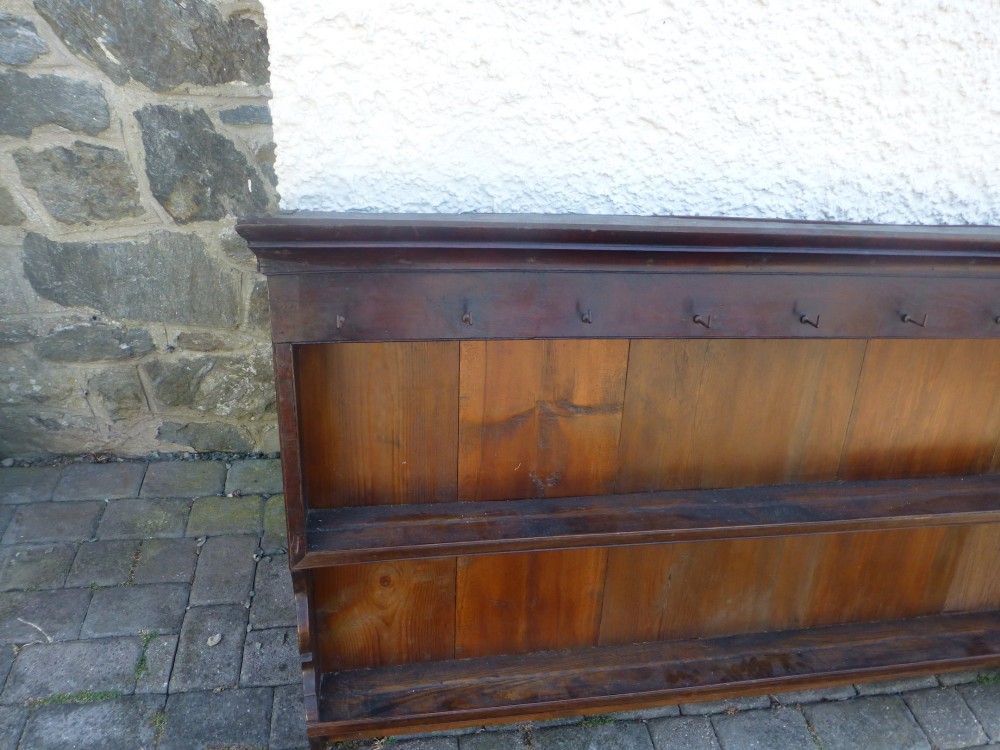 An 18th-century dark oak delft plate rack featuring two wide display shelves, a planked backboard, a moulded cornice, and metal cup hooks along the top rail. View II