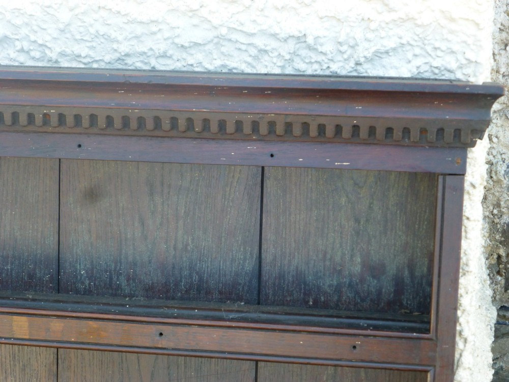 An 18th-century Georgian dark oak delft plate rack featuring three horizontal open display shelves and a dentil moulded top cornice. View II