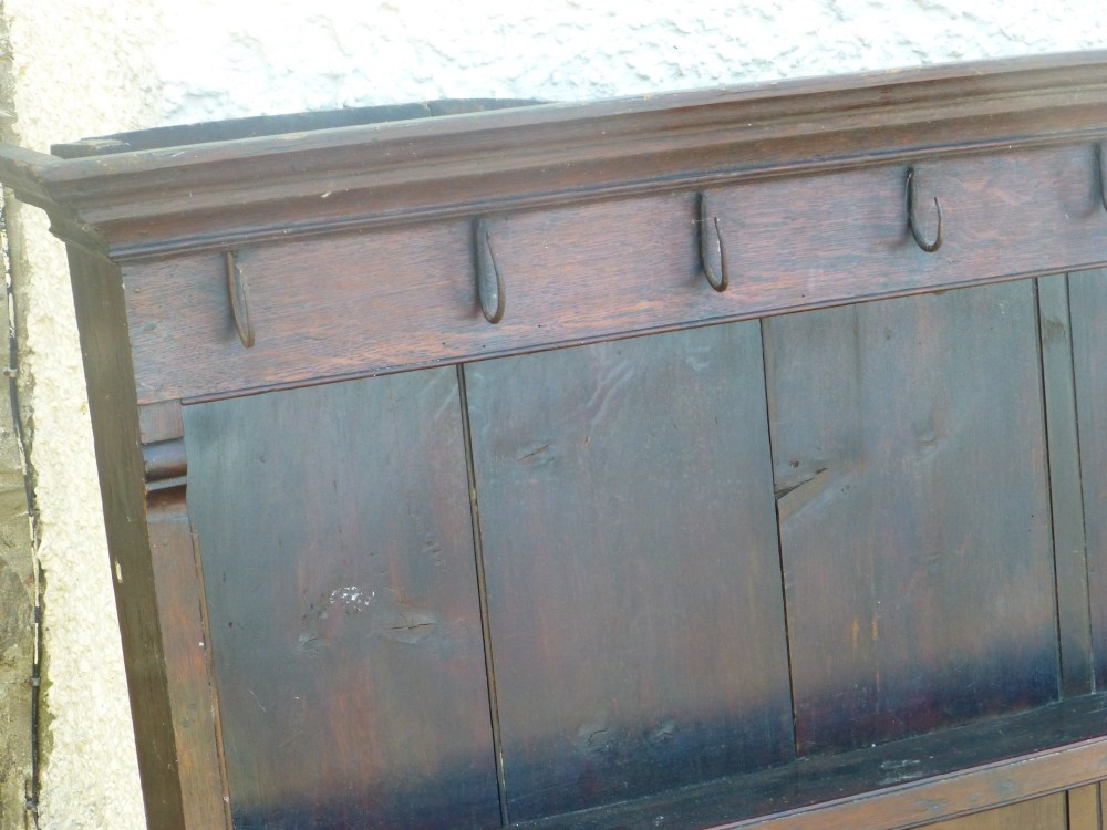 An 18th-century Georgian dark oak delft plate rack featuring three horizontal display shelves, vertical backboard planks, a moulded top cornice, and iron cup hooks. View II
