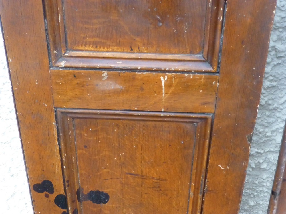 A pair of tall, narrow antique pine cupboard doors featuring a two-panel design and a warm brown scumbled faux oak paint finish. View II