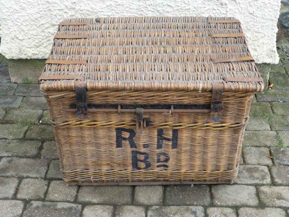 A large 19th-century woven brown wicker travelling trunk with iron latches and stencilled black lettering on the front.