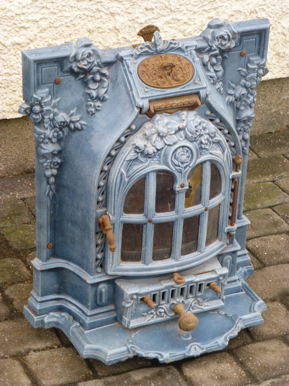 A French Art Nouveau slate blue enamelled cast iron log burner stove adorned with floral relief mouldings and an arched windowed door. View II