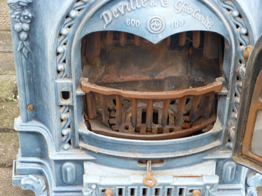 A French Art Nouveau slate blue enamelled cast iron log burner stove adorned with floral relief mouldings and an arched windowed door. View V