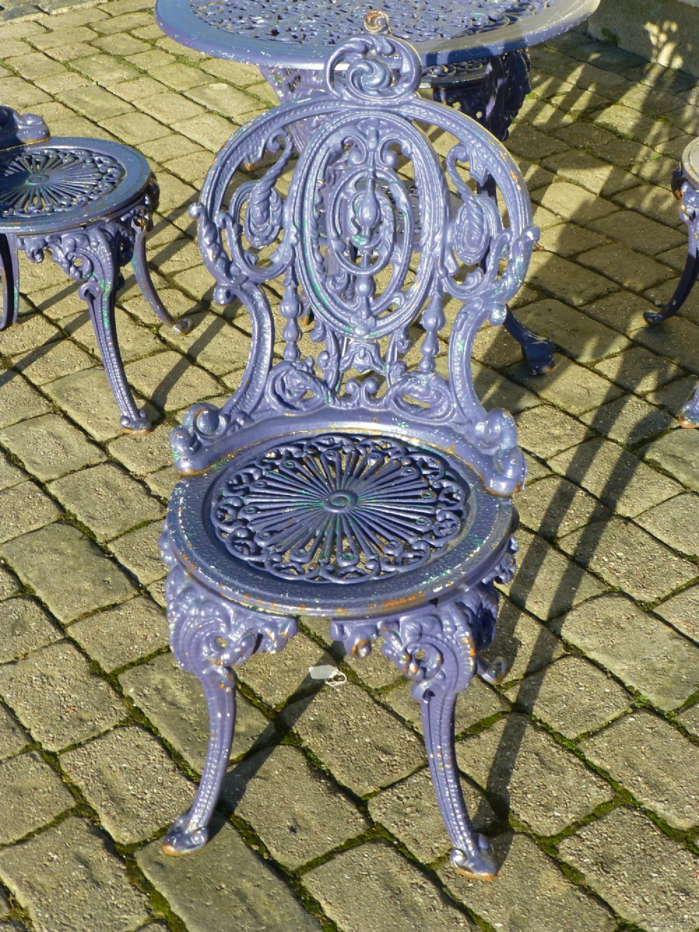 A nineteenth-century painted purple cast iron garden suite consisting of a round openwork table and four matching ornate medallion chairs. View II