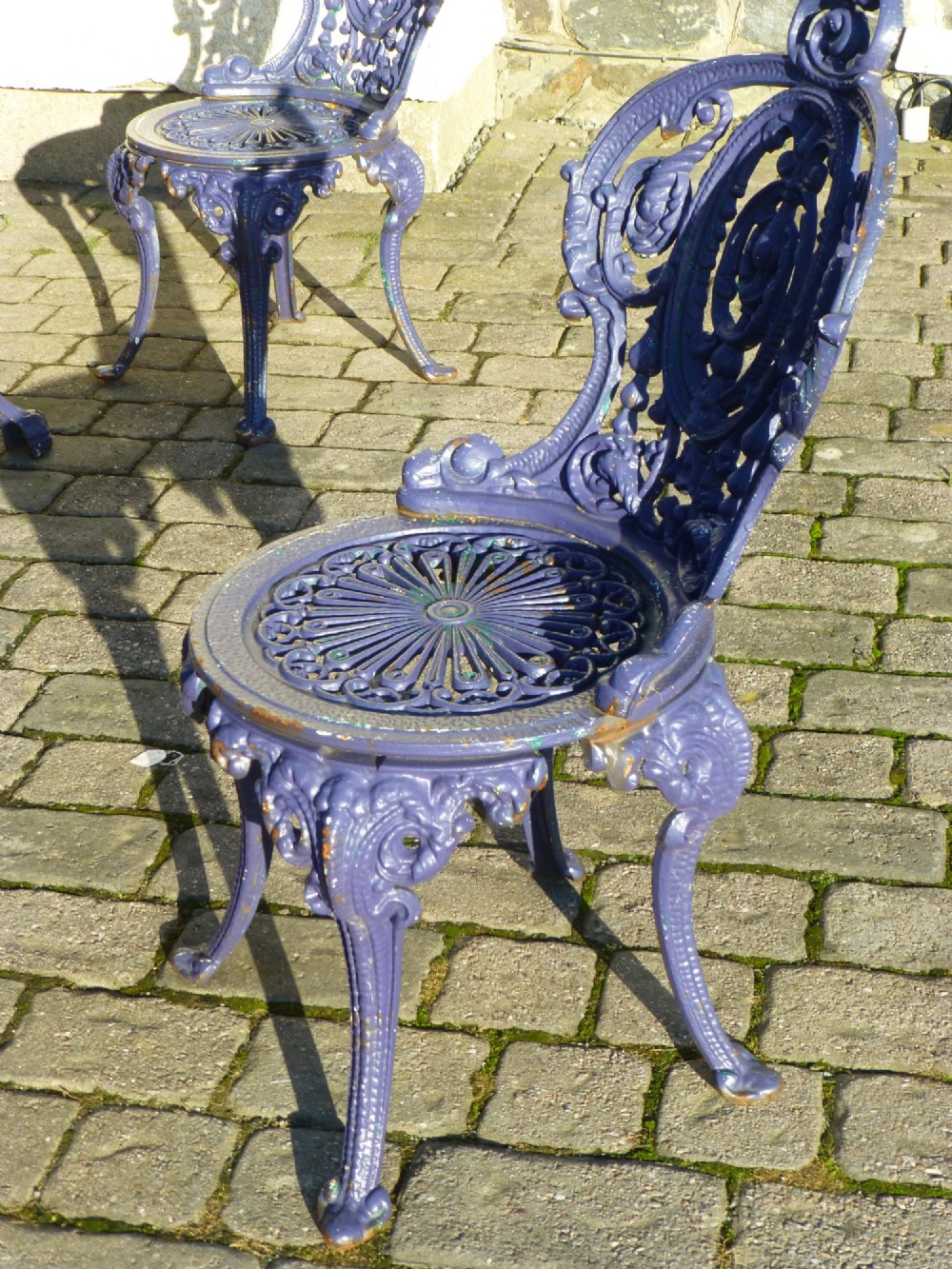A nineteenth-century painted purple cast iron garden suite consisting of a round openwork table and four matching ornate medallion chairs. View III