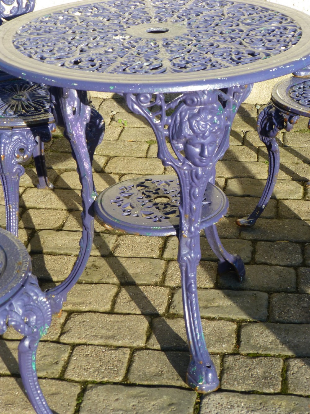 A nineteenth-century painted purple cast iron garden suite consisting of a round openwork table and four matching ornate medallion chairs. View IV
