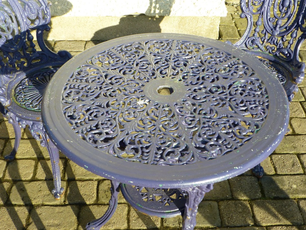 A nineteenth-century painted purple cast iron garden suite consisting of a round openwork table and four matching ornate medallion chairs. View V
