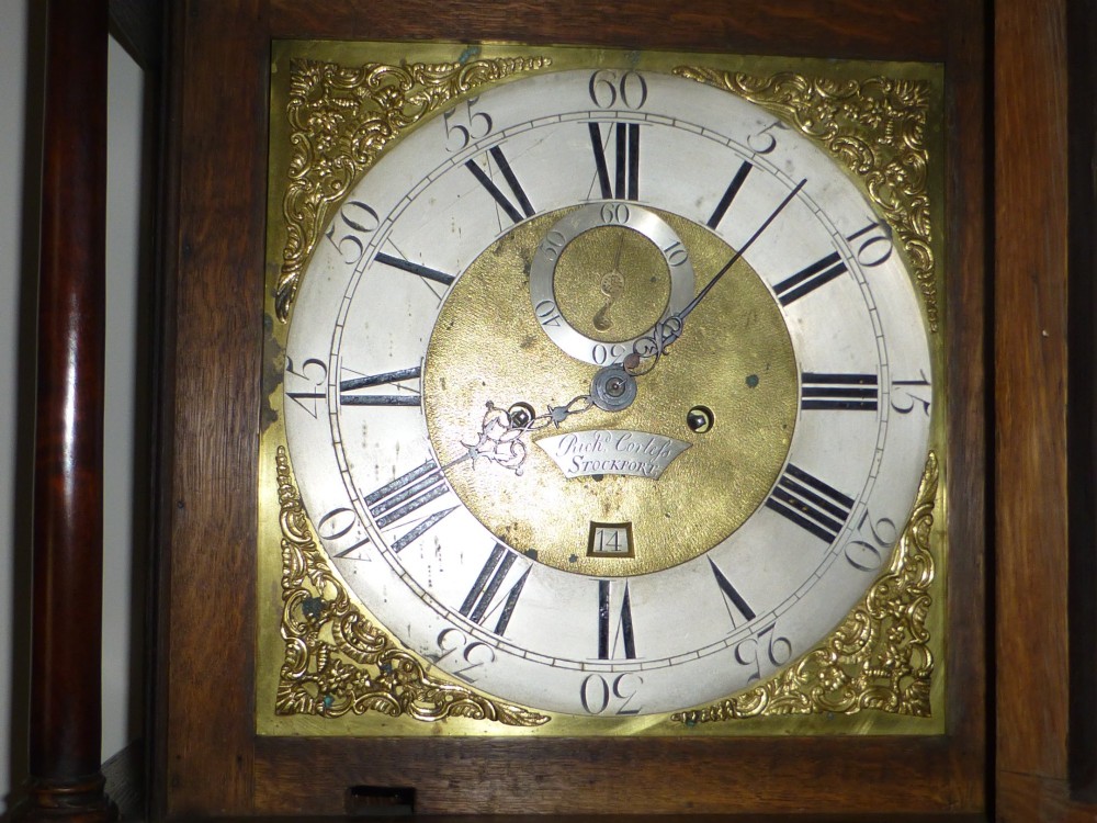 An eighteenth-century dark oak and walnut longcase clock featuring a square brass dial, turned columns, and a hood with a moulded cornice. View VIII