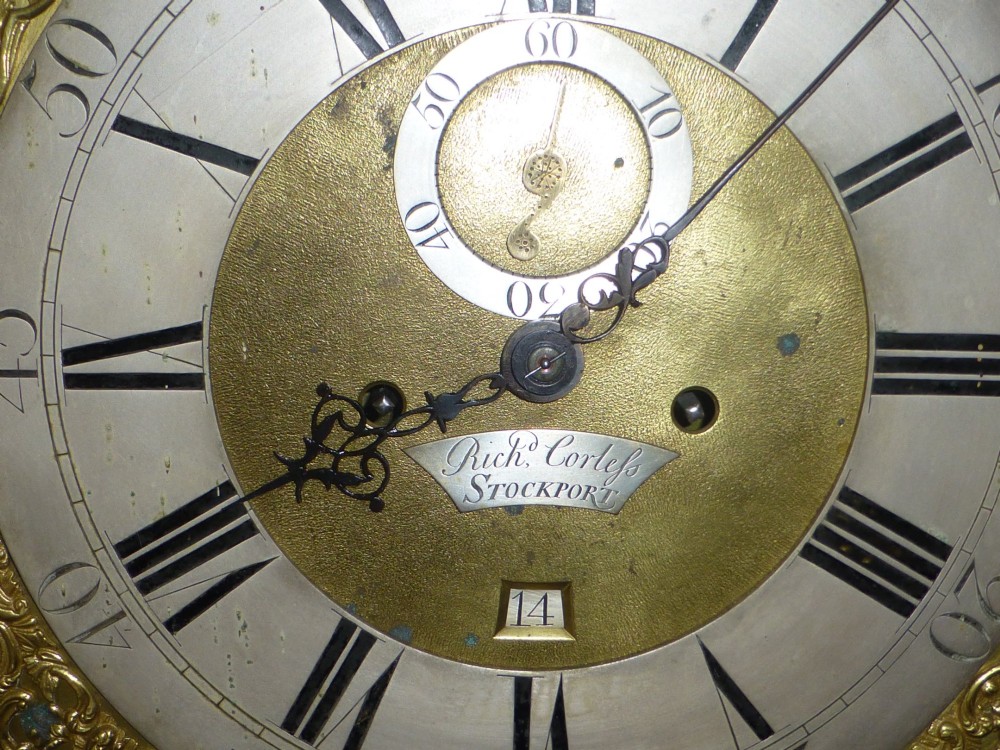 An eighteenth-century dark oak and walnut longcase clock featuring a square brass dial, turned columns, and a hood with a moulded cornice. View IX