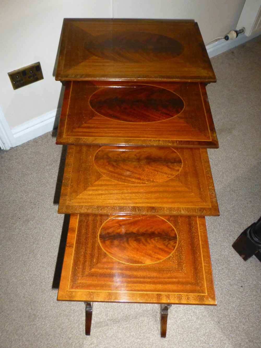 A set of four graduated mahogany nesting tables featuring oval inlay motifs and turned wooden legs, stacked in a cascading arrangement. View II