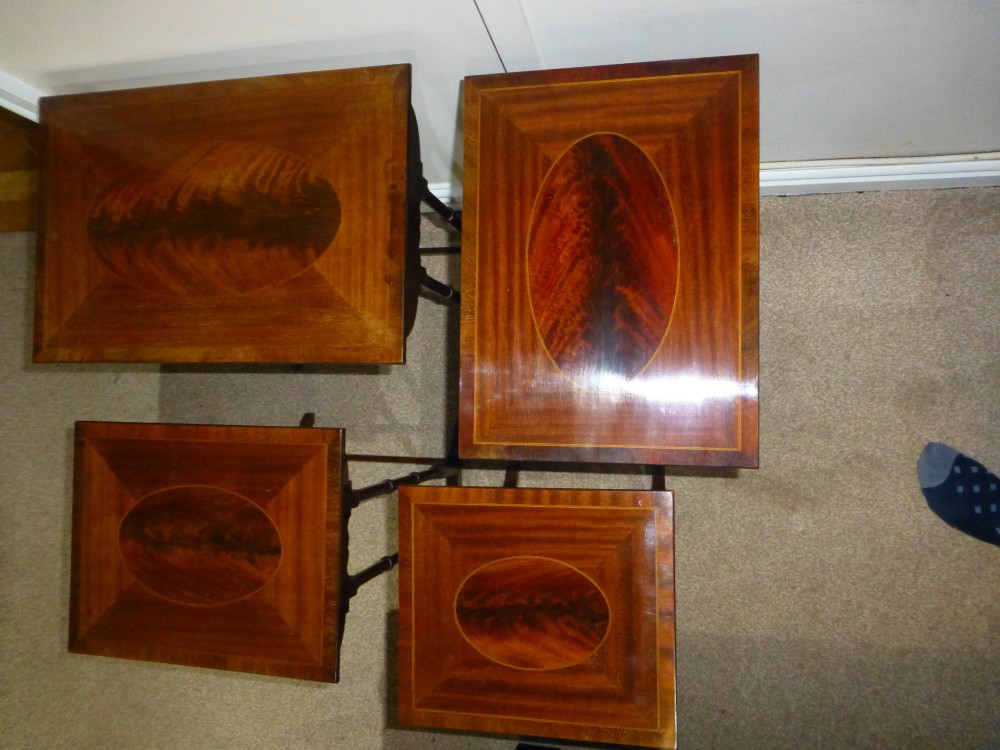 A set of four graduated mahogany nesting tables featuring oval inlay motifs and turned wooden legs, stacked in a cascading arrangement. View III