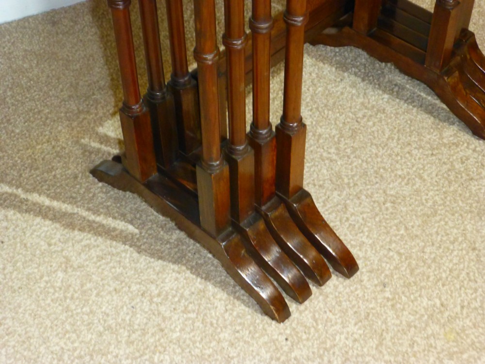 A set of four graduated mahogany nesting tables featuring oval inlay motifs and turned wooden legs, stacked in a cascading arrangement. View VII
