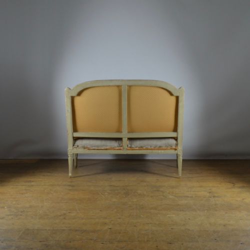 fig 1. A 19th-century French Louis XVI style settee featuring a distressed grey painted carved wooden frame, fluted legs, and neutral grey linen upholstery.
