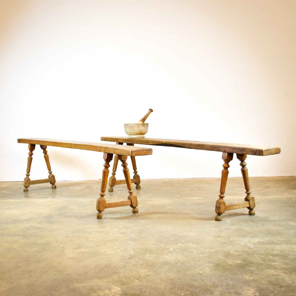 A pair of long French cherrywood benches featuring narrow plank seats and turned legs connected by low stretchers.