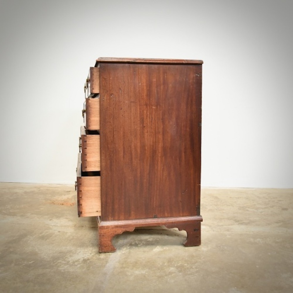 A George III mahogany chest of drawers featuring two short over three long drawers with brass swan-neck handles and bracket feet. View III