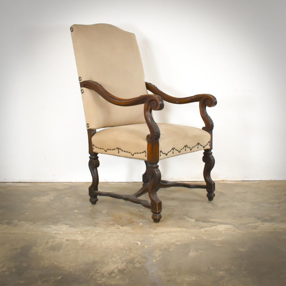 A late 19th-century French Os de Mouton armchair featuring carved timber scroll arms, serpentine stretchers, neutral fabric upholstery, and decorative stud detail.