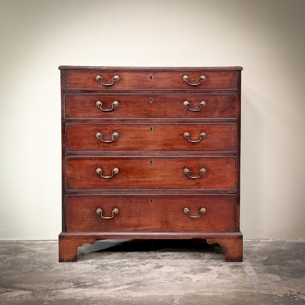 A George III mahogany chest of drawers featuring five graduated drawers with brass swan-neck handles, resting on bracket feet.