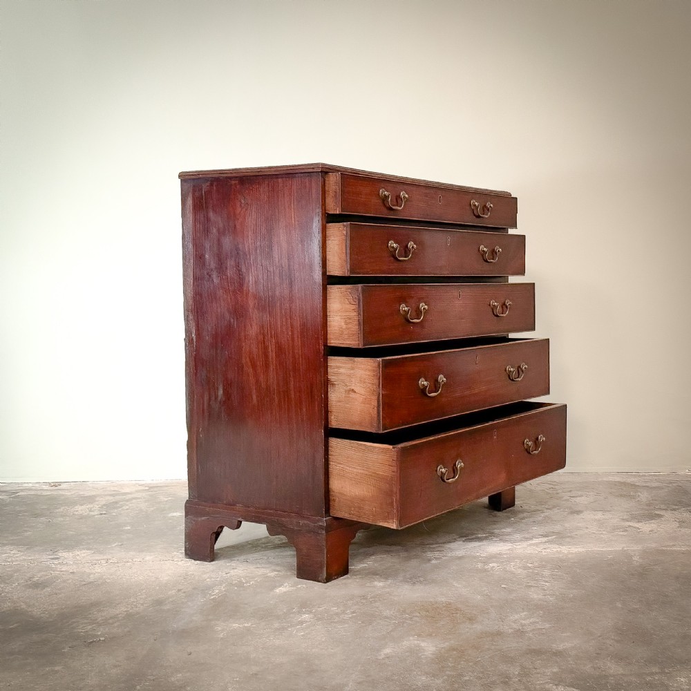 A George III mahogany chest of drawers featuring five graduated drawers with brass swan-neck handles, resting on bracket feet. View II