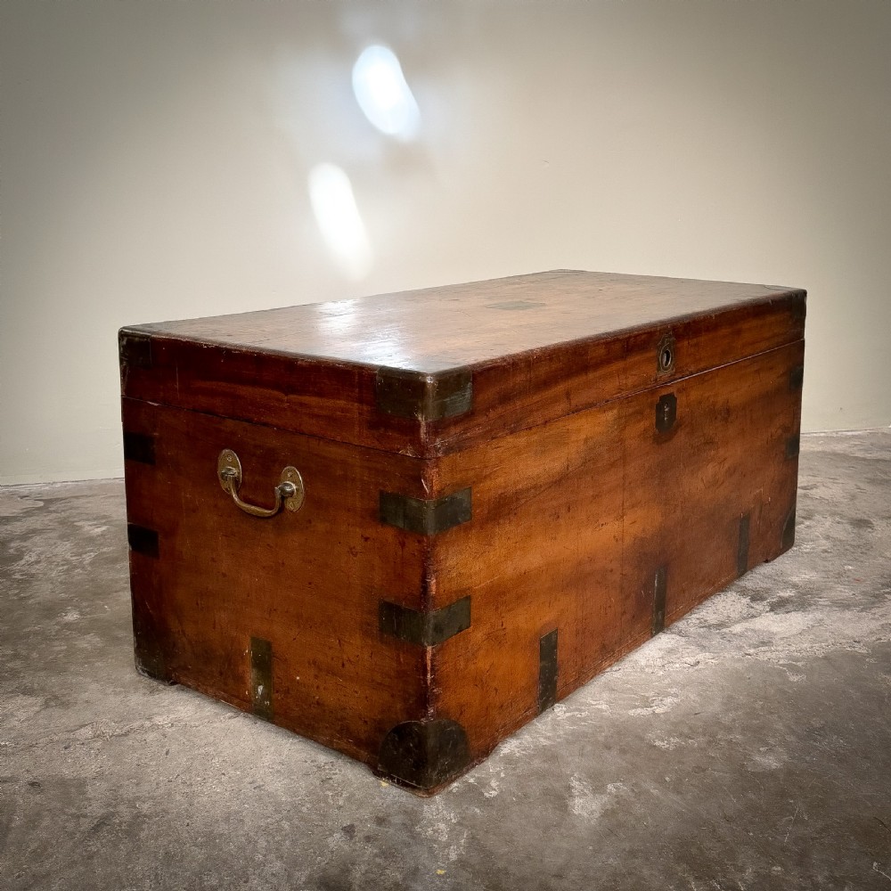 A rectangular warm brown camphor wood trunk featuring flush brass corner brackets, strap mounts, and a central brass keyhole escutcheon. View II