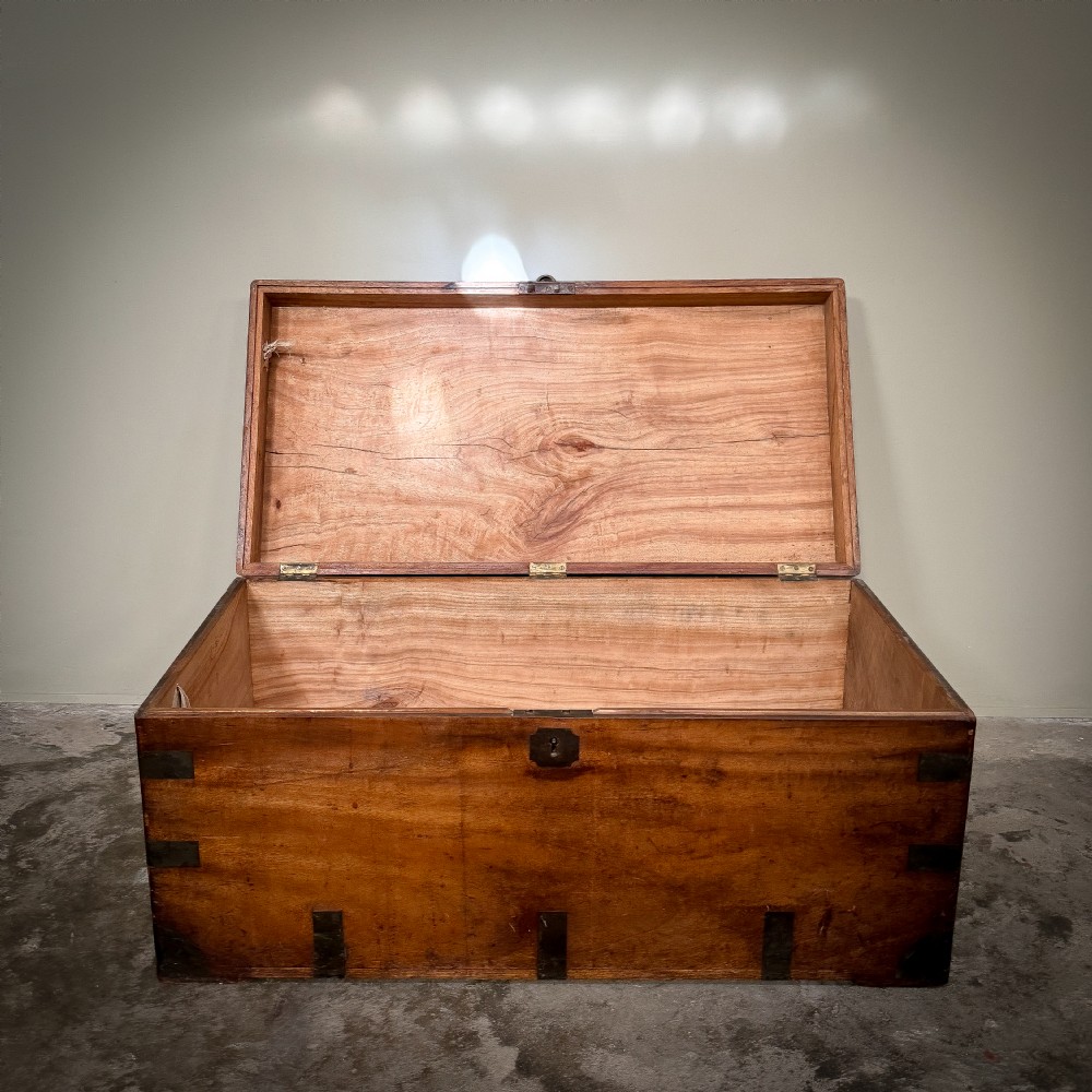 A rectangular warm brown camphor wood trunk featuring flush brass corner brackets, strap mounts, and a central brass keyhole escutcheon. View III