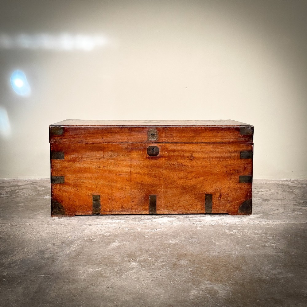 A rectangular warm brown camphor wood trunk featuring flush brass corner brackets, strap mounts, and a central brass keyhole escutcheon. View IV