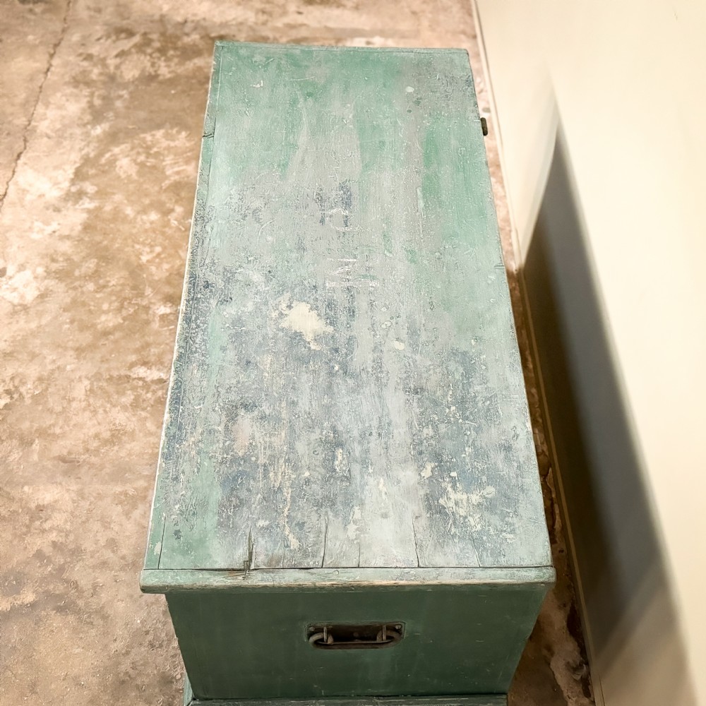 A large rectangular green painted pine blanket box with a flat hinged lid, a dark keyhole escutcheon, and a simple plinth base. View V