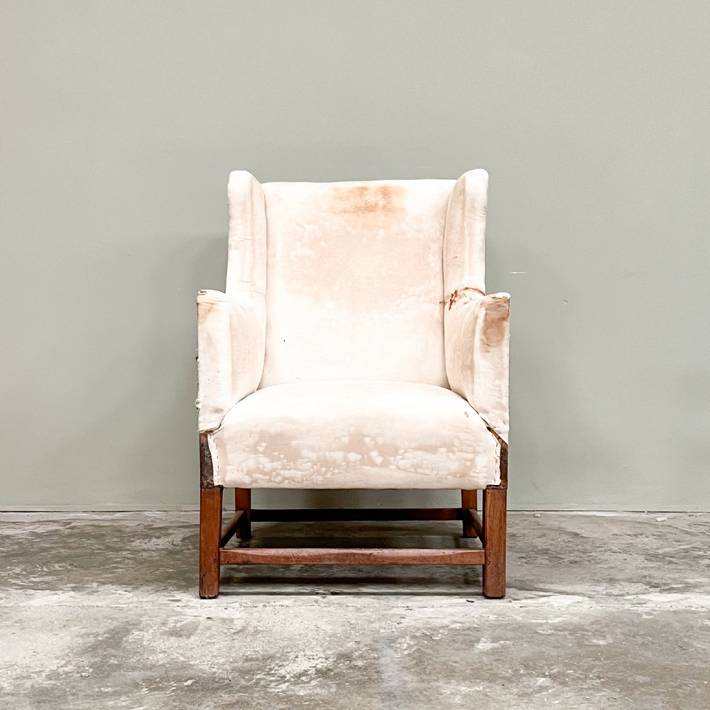 A 19th-century wingback armchair frame lined in cream calico fabric with exposed wooden side structure and square timber legs. View IV