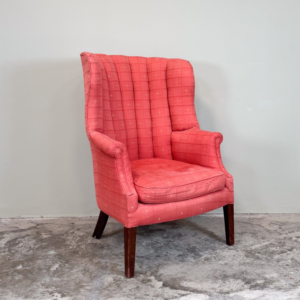 A red patterned upholstered barrel back armchair featuring vertical channel stitching, a fitted seat cushion, and dark wooden legs.