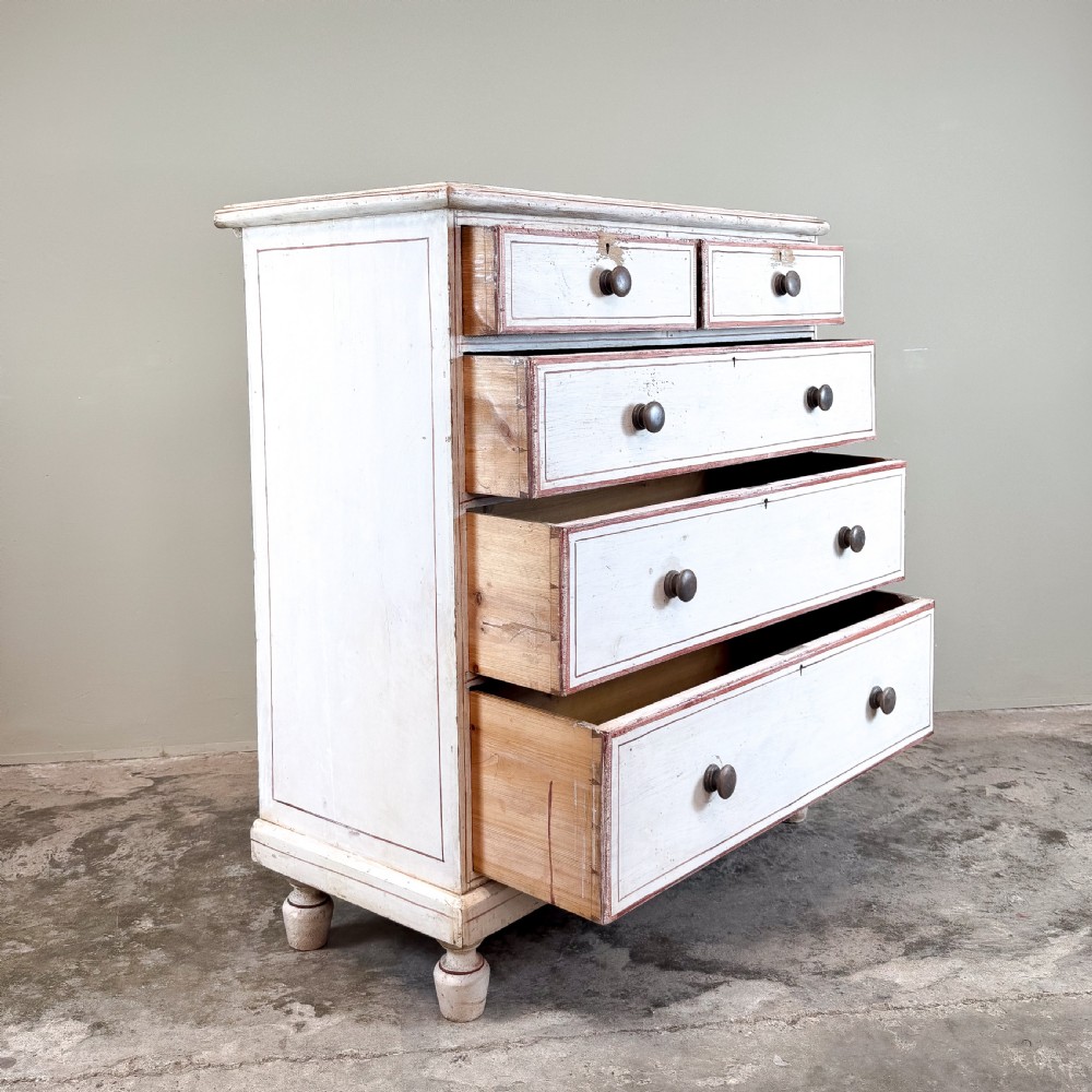 A 19th-century painted pine chest of drawers featuring five drawers with dark turned wooden knobs and red painted line details on an off-white background. View II