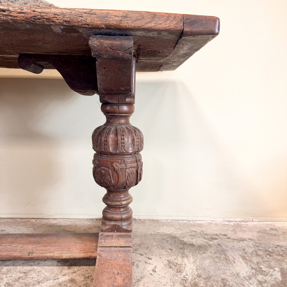 A seventeenth-century oak console table featuring heavily carved cup-and-cover supports and a stretcher base against a neutral wall. View II