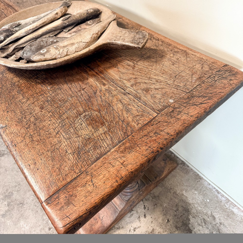 A seventeenth-century oak console table featuring heavily carved cup-and-cover supports and a stretcher base against a neutral wall. View III
