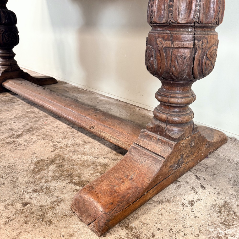 A seventeenth-century oak console table featuring heavily carved cup-and-cover supports and a stretcher base against a neutral wall. View IV