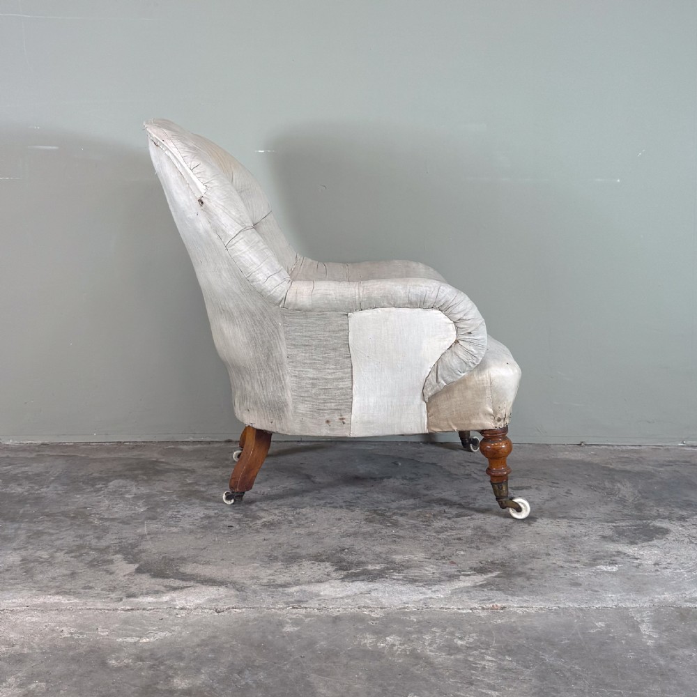 A 19th-century Victorian Howard style armchair upholstered in light cream fabric with deep button back tufting and turned wooden legs on brass castors. View III